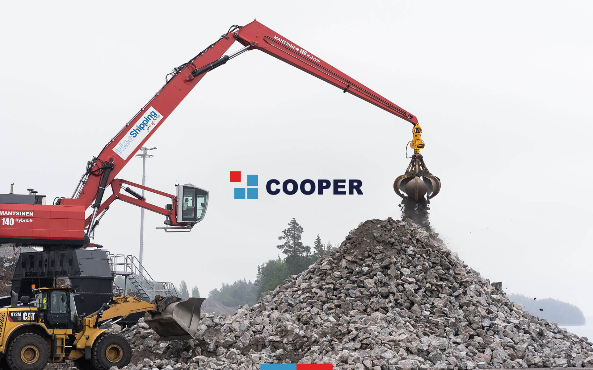 Large red excavator lifting rocks at a construction site