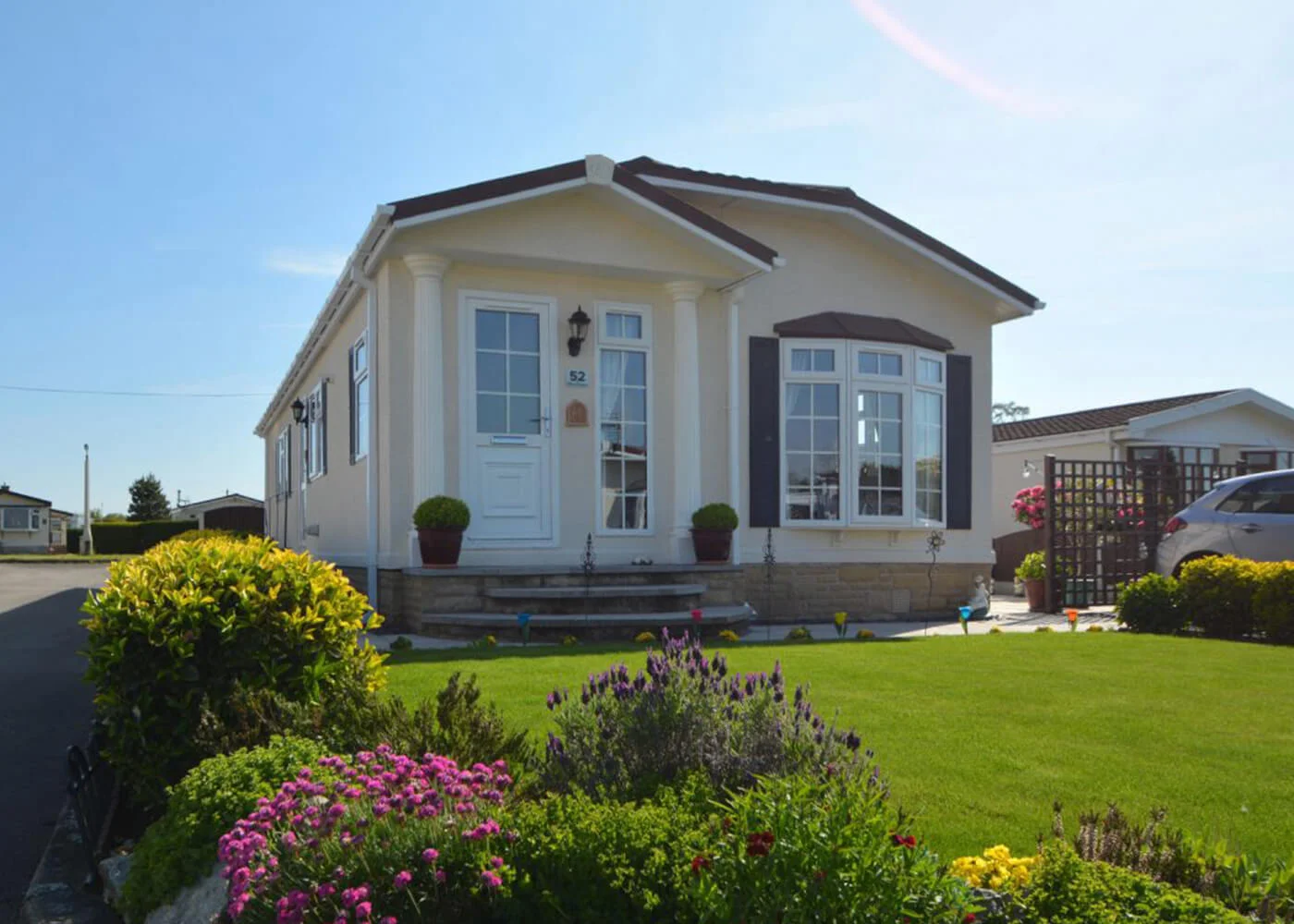 Charming Modern Home with Beautiful Garden Exterior view of a modern home surrounded by colorful flowers and a well-maintained lawn
