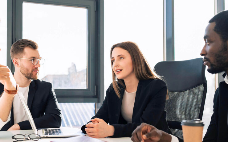 A diverse group of professionals engaged in a discussion around a conference table in a modern office.