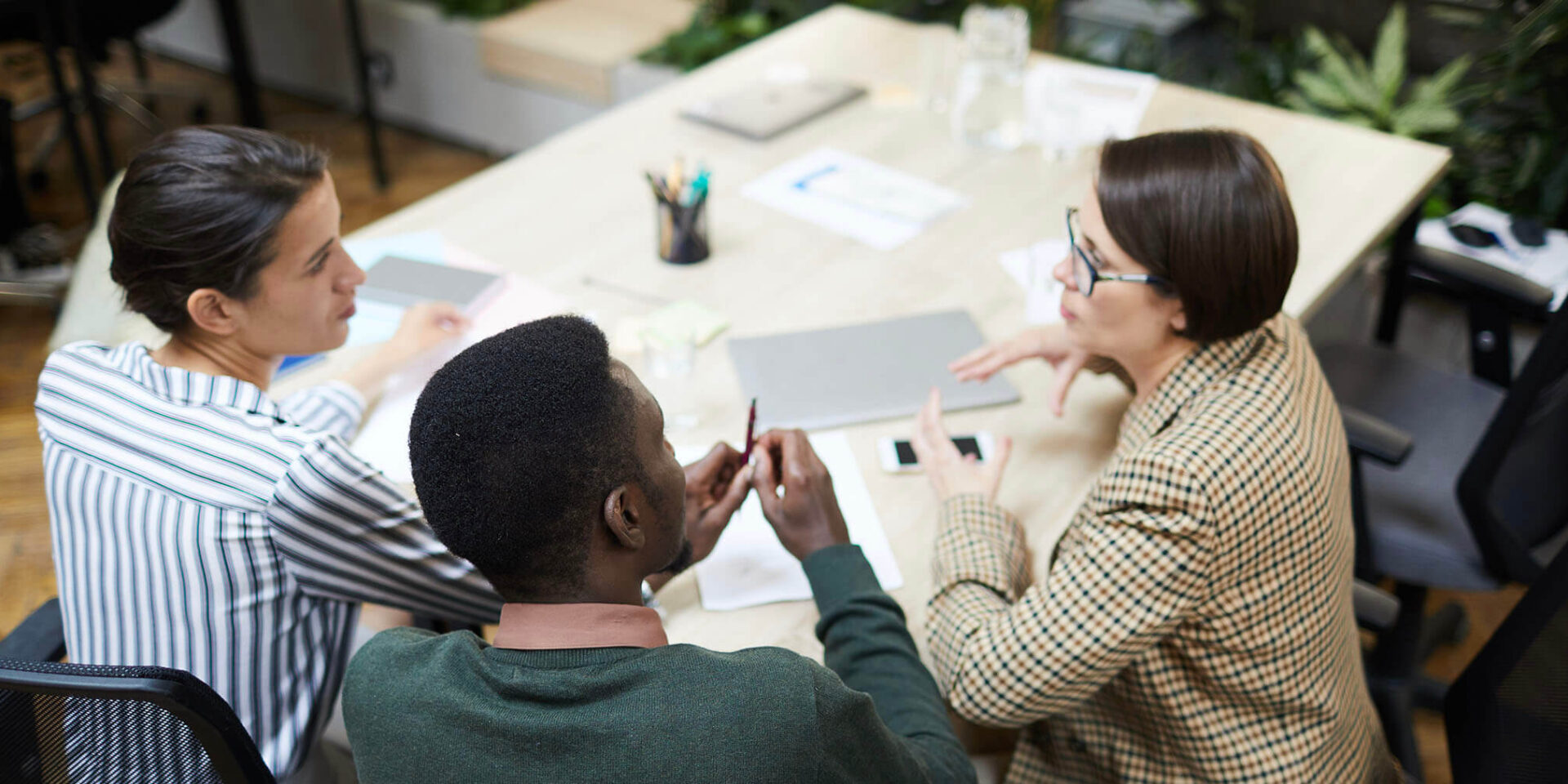 Three professionals engaged in a meeting at a modern office, discussing ideas and strategies.