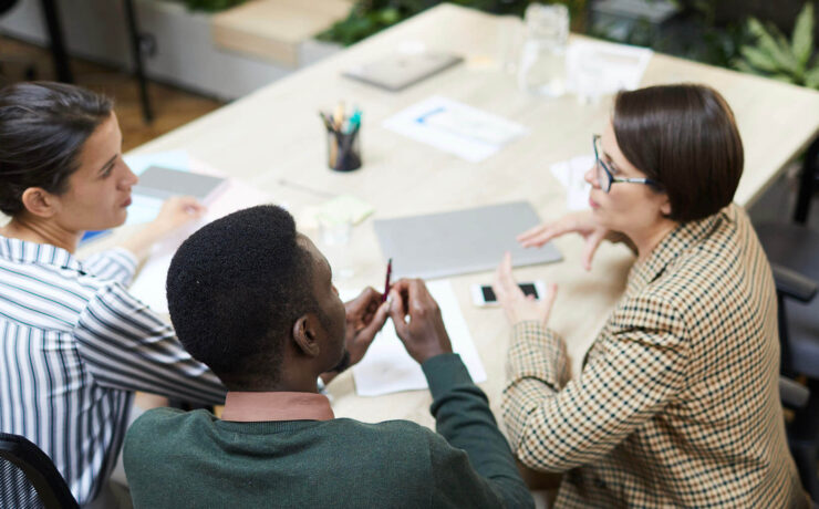 Three professionals engaged in a meeting at a modern office, discussing ideas and strategies.